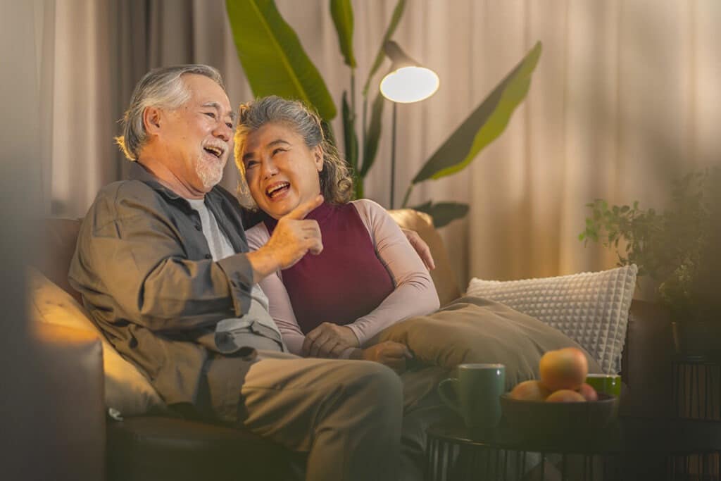 old retired age asian couple watching tv homeold mature asian couple cheering sport games competition together with laugh smile victory sofa couch living room home isolation activity